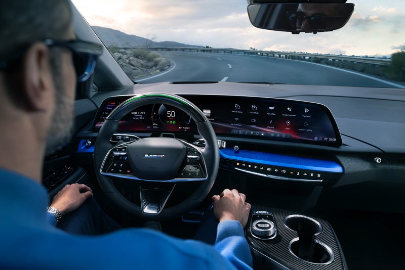 Front View of the 2026 OPTIQ-V Driving Through the Dusk Utilizing its Headlights | McDonald Cadillac in Saginaw MI