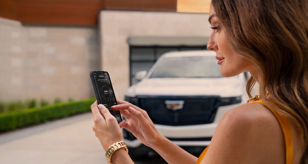 lady checking her mobile with a Cadillac vehicle background | McDonald Cadillac in Saginaw MI